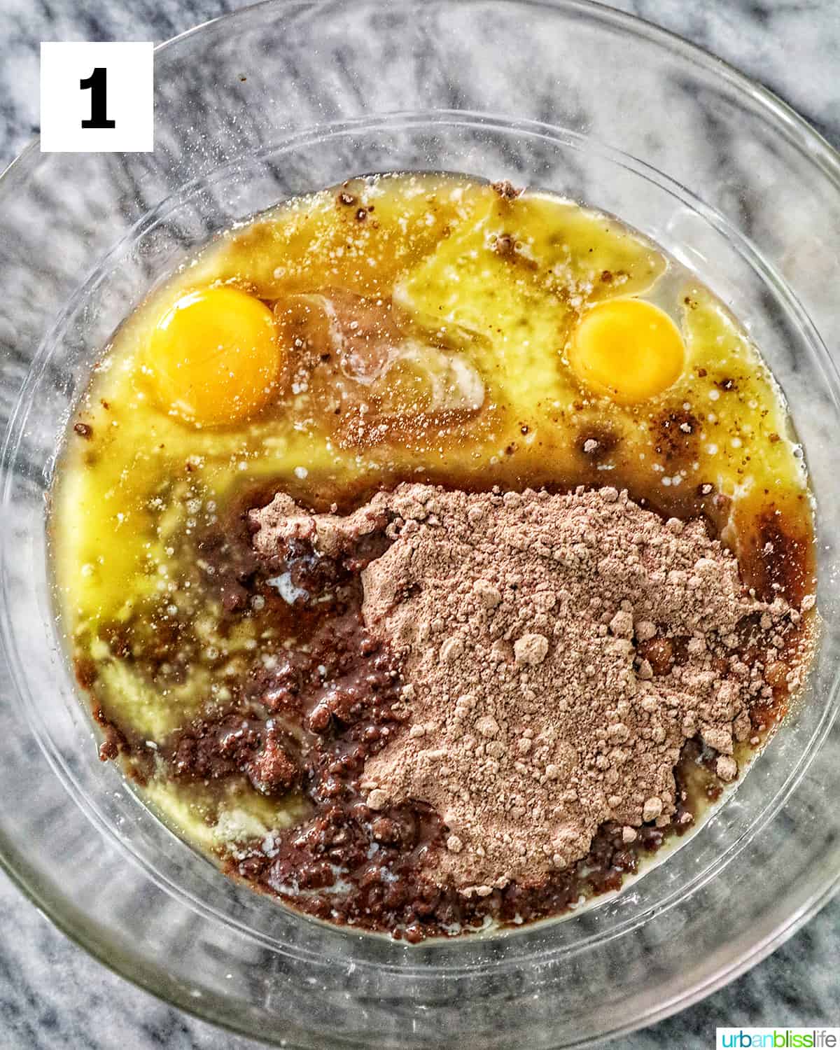 eggs and chocolate cake mix in a glass bowl on marble table.