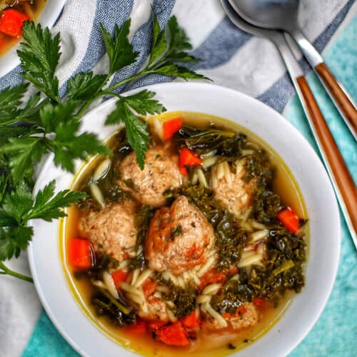 single white bowl of Italian Wedding Soup with two spoons