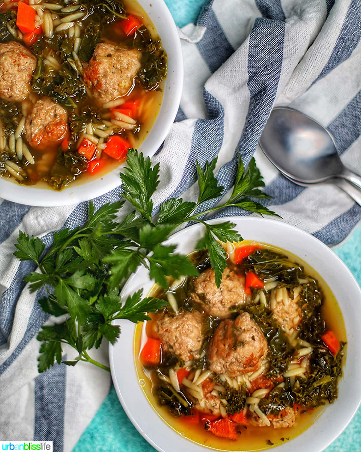 two bowls of instant pot Italian Wedding Soup with two spoons and parsley garnish.