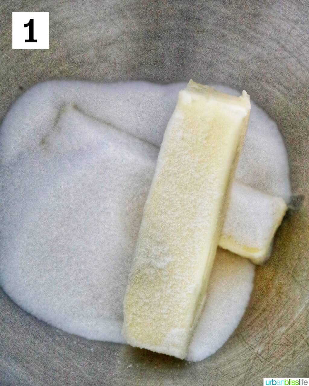 sticks of butter with granulated sugar in a stand mixer bowl.