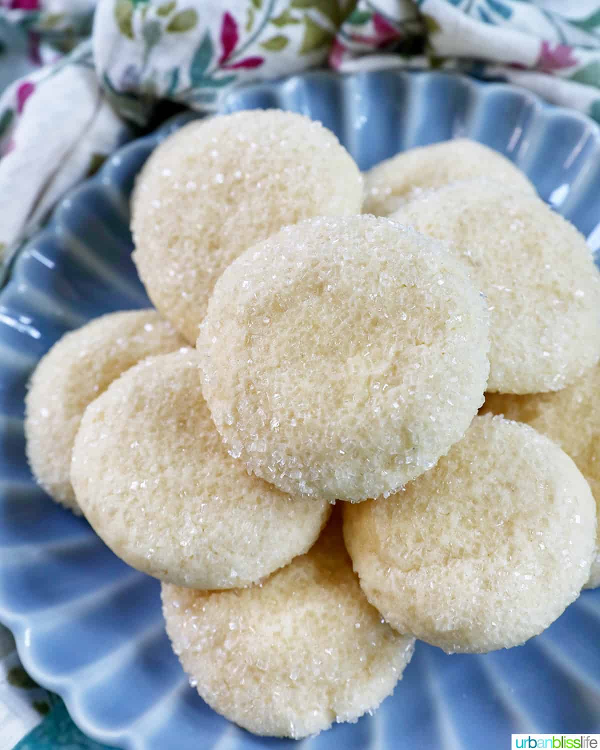 several soft almond sugar cookies stacked on top of one another on a blue plate.