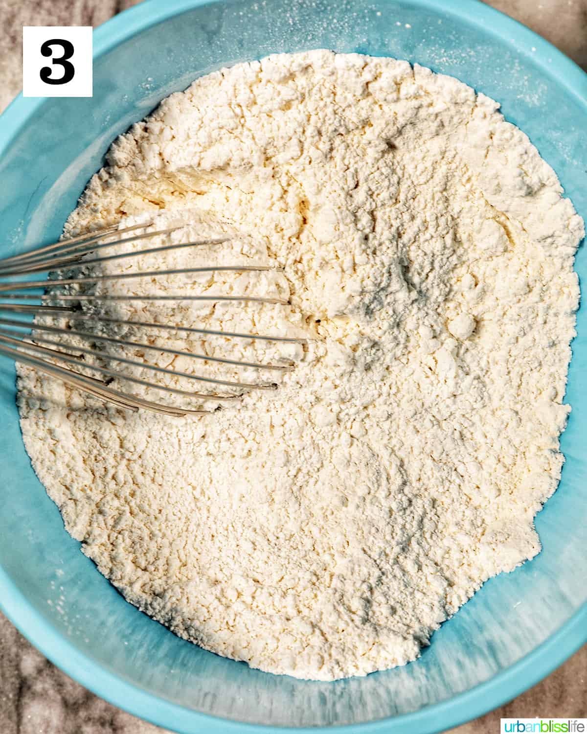 whisk in dry ingredient flour mix in a blue bowl.