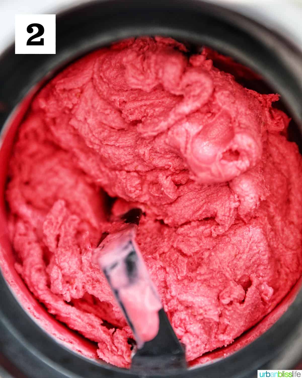 ice cream maker filled with raspberry sherbet mixing.