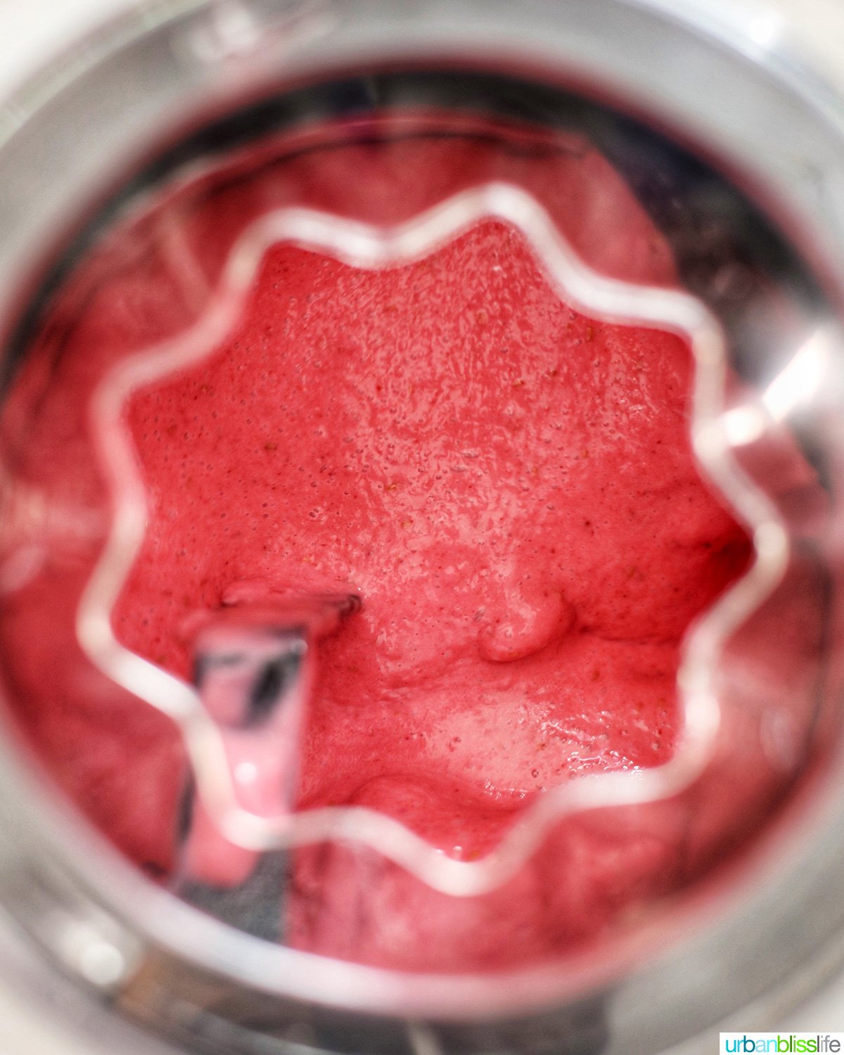 ice cream maker filled with liquid raspberry sherbet mixing into an ice cream..