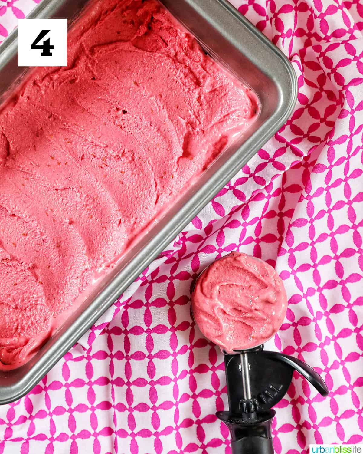 pan full of raspberry sherbet with side of ice cream scoop filled with raspberry sherbet on a pink and white napkin.