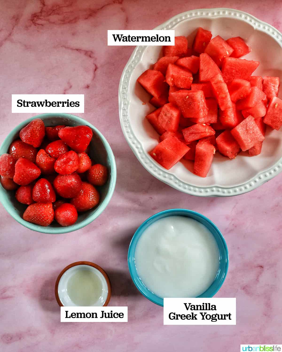 bowls of ingredients to make strawberry watermelon smoothies on a pink table.