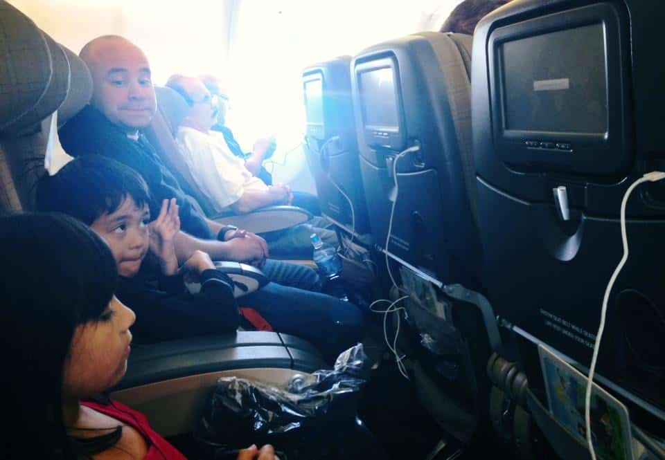 daughter and son on a plane watching tv