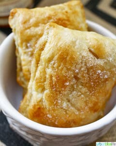 two apple whiskey hand pies in a white bowl.