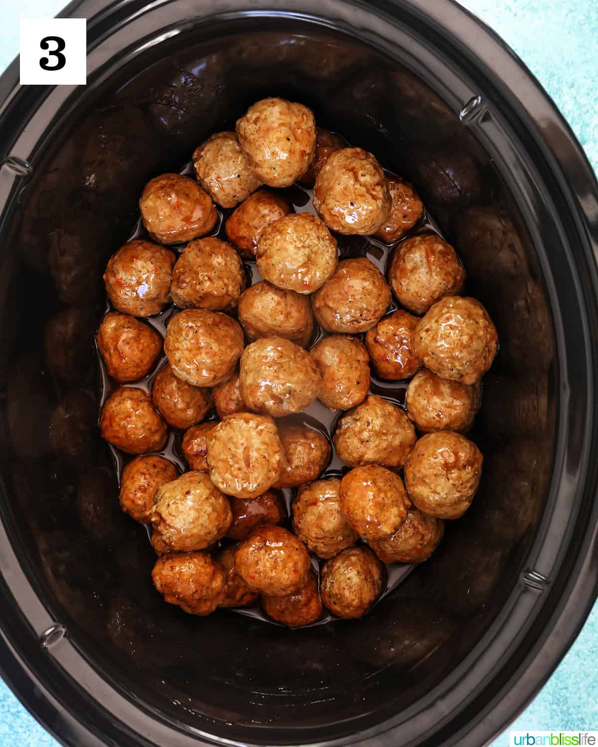sauce poured over dozens of meatballs in a slow cooker.