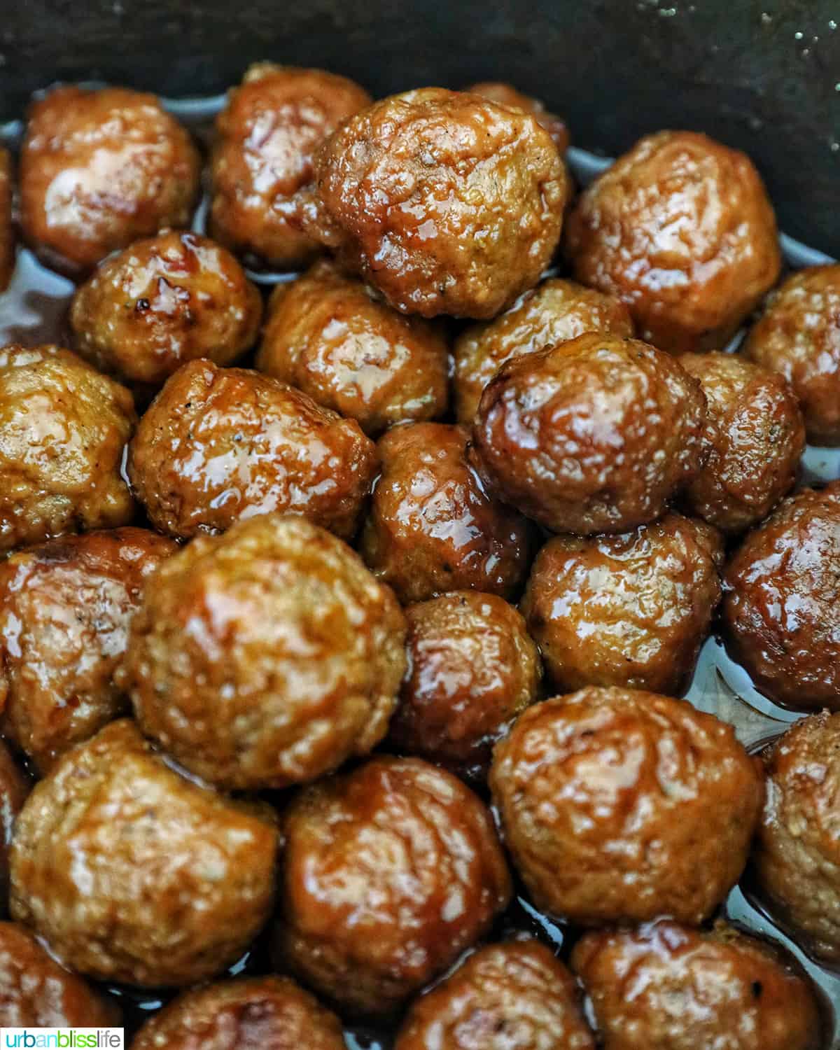 dozens of cooked honey bourbon meatballs in a slow cooker.