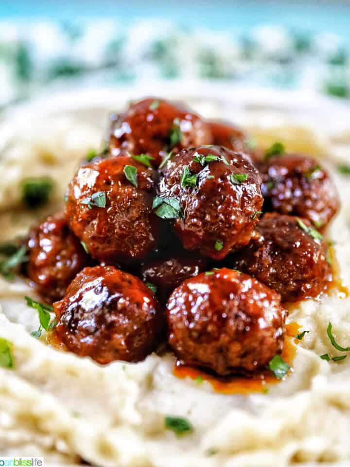 side view of slow cooker honey bourbon meatballs on a bed of mashed potatoes.