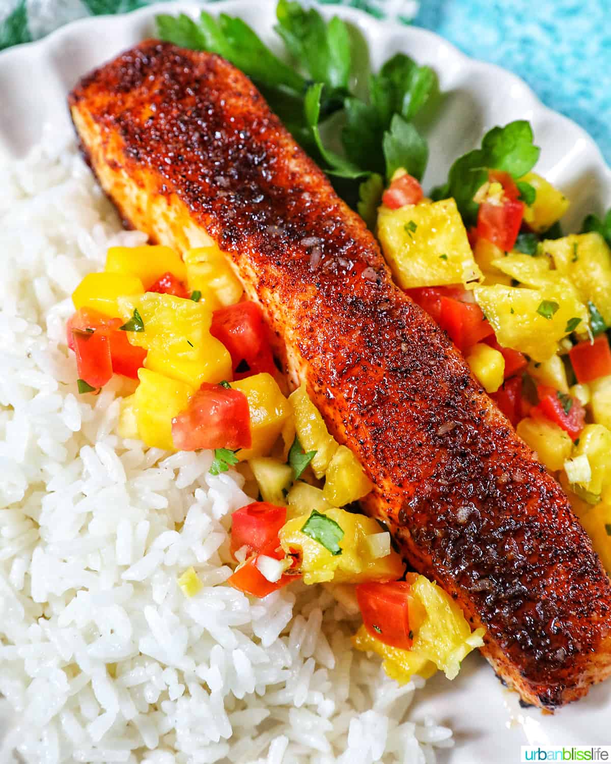 air fryer salmon with mango pico de gallo salsa, white rice, and parsley on a plate.