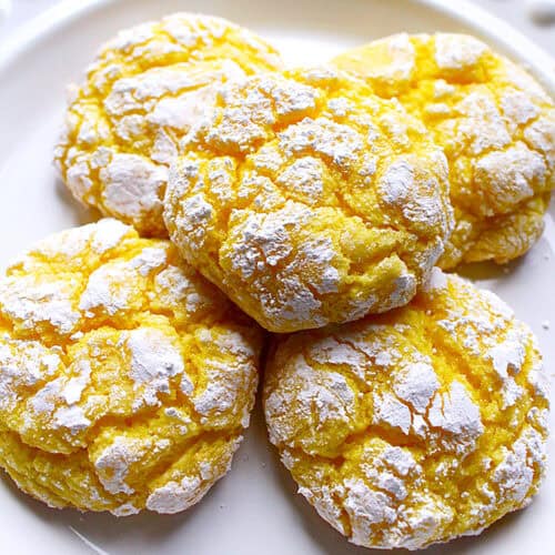 stack of lemon crinkles cookies on a white plate.
