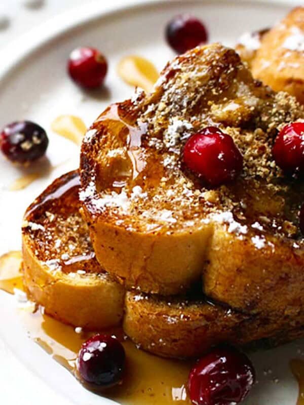 stack of brioche french toast on a white plate with cranberries.
