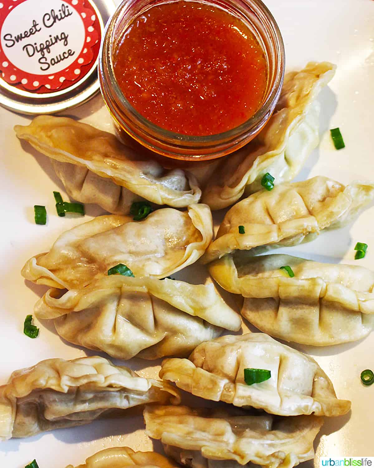 jar of sweet chili dipping sauce with dumplings on a white plate.