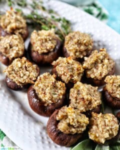 Vegan Stuffed Mushrooms close together on a white platter. with thyme leaves