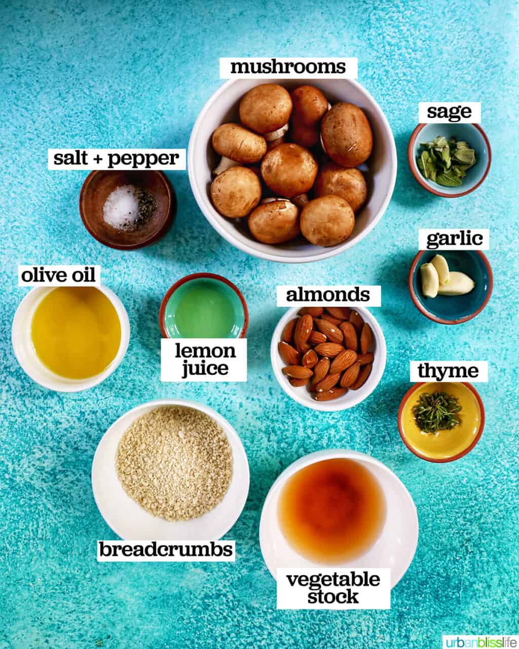bowls of ingredients to make Vegan Stuffed Mushrooms with ingredient labels next to each one on a blue background.