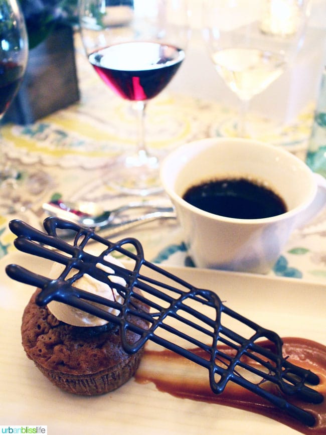 chocolate fancy dessert on a white plate with white cup of coffee in background.