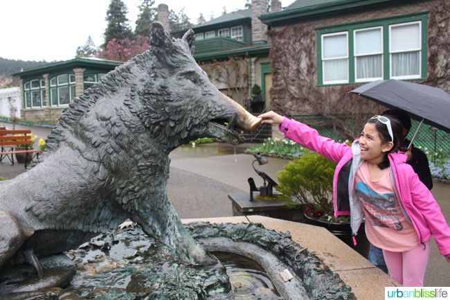 girl touching boar statue at Butchart Gardens