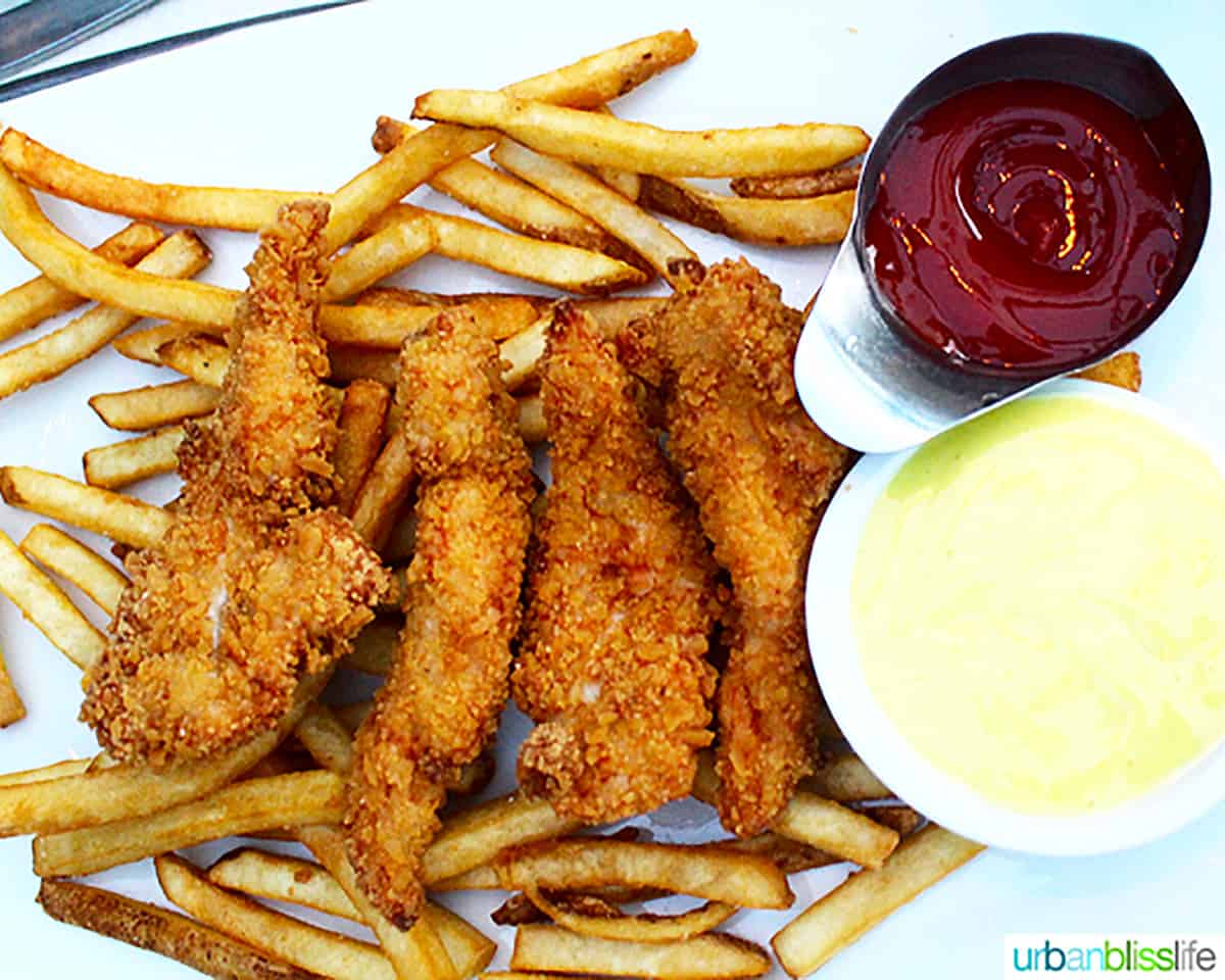 breaded chicken tenders on french fries with ketchup and honey mustard.