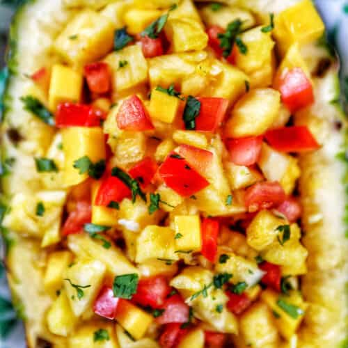 chopped pineapple, mango, tomatoes, and onions in a hollowed out pineapple.