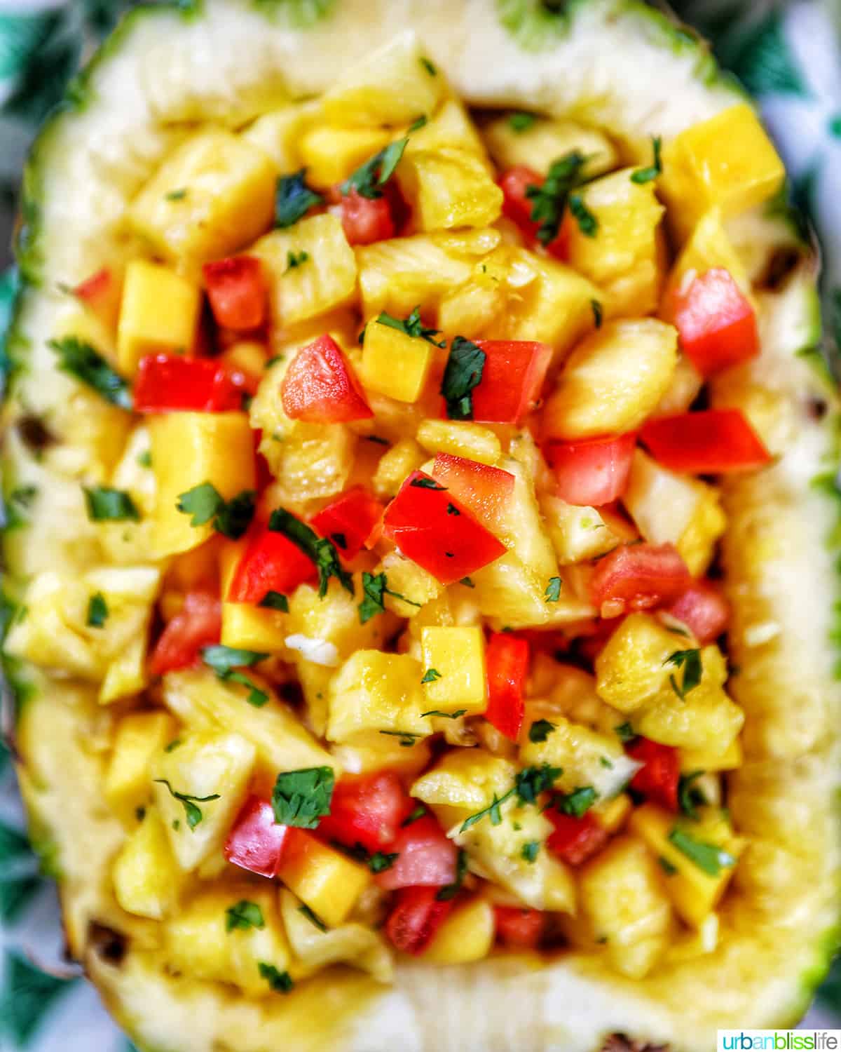 chopped pineapple, mango, tomatoes, and onions in a hollowed out pineapple.