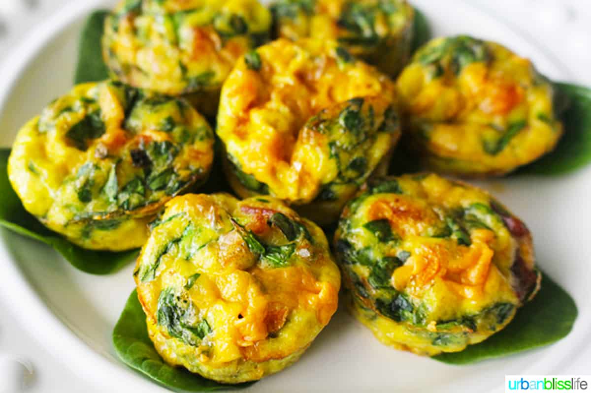 several cheesy spinach mini frittatas on a white plate.