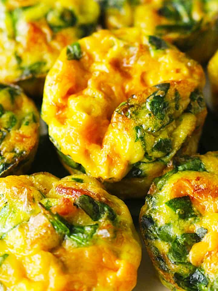 several cheesy spinach mini frittatas stacked.