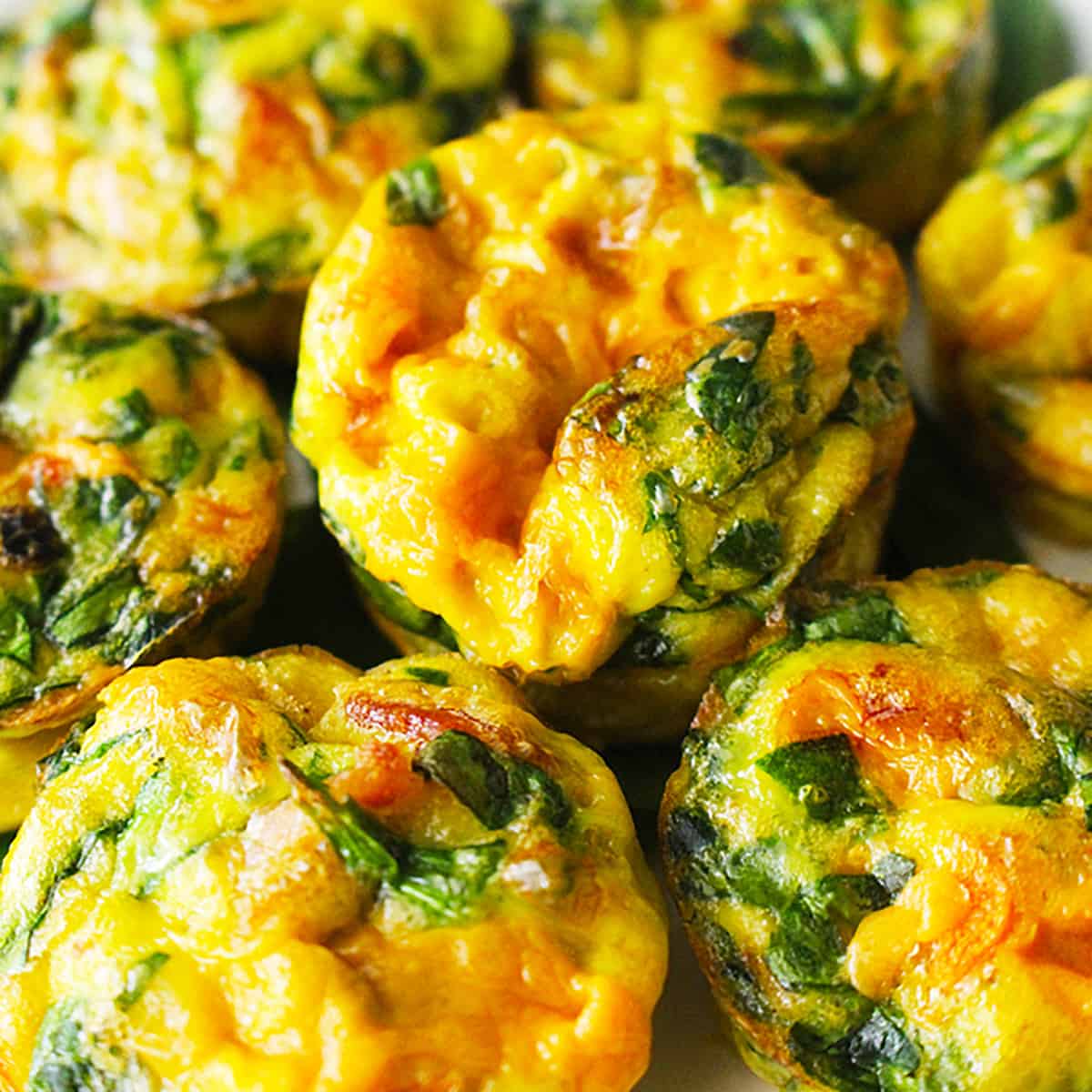 several cheesy spinach mini frittatas stacked.