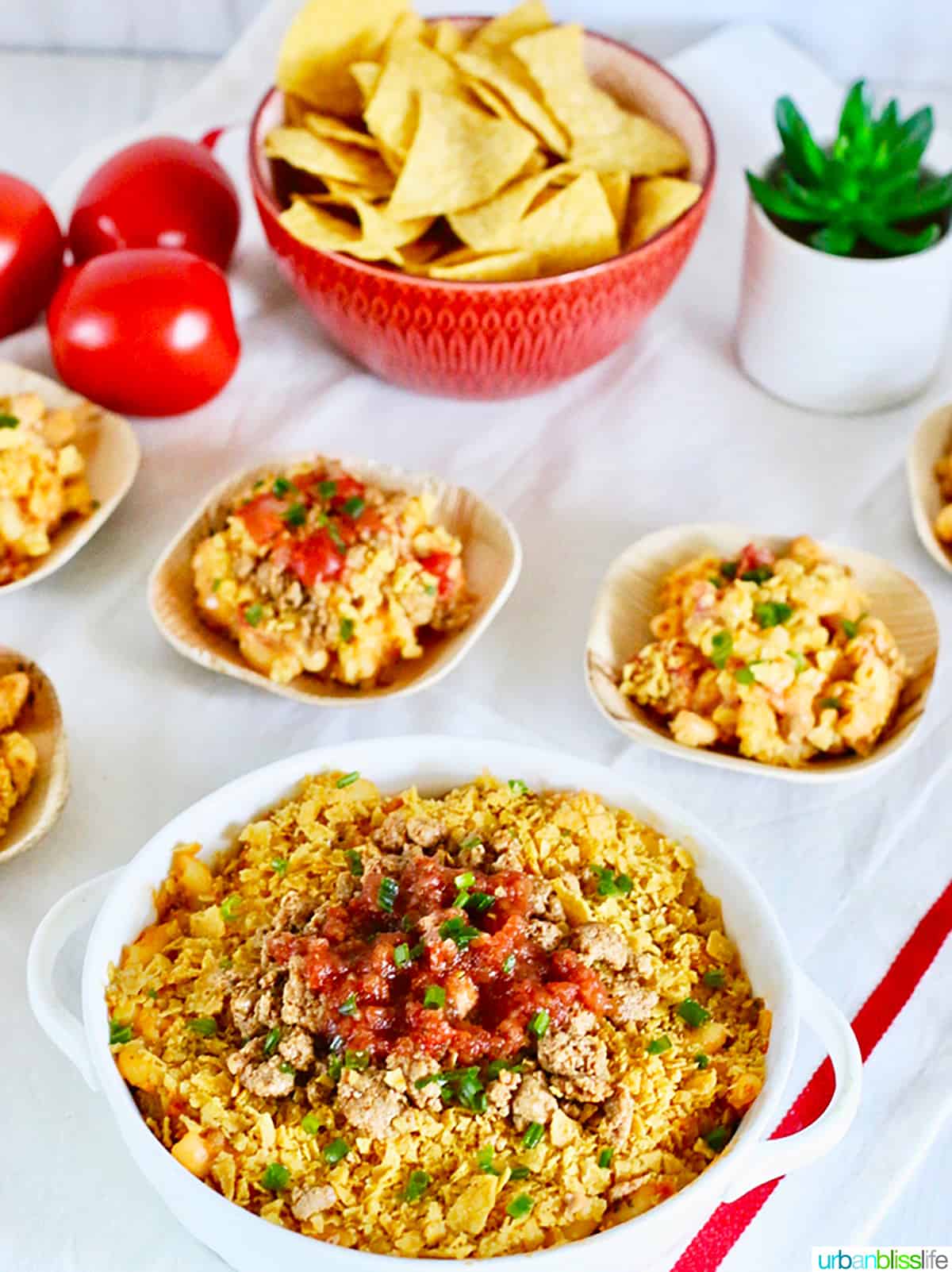 small bowls of taco mac and cheese with a bowl of tortilla chips and some tomatoes on the side.
