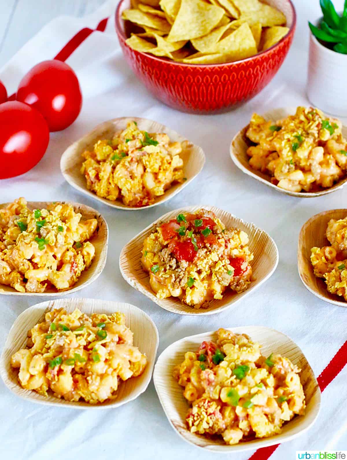 small bowls of taco mac and cheese with a bowl of tortilla chips and some tomatoes on the side.