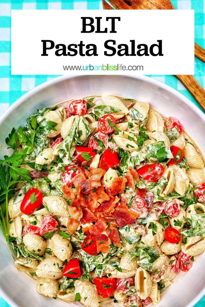 BLT pasta salad in a white bowl with wooden serving spoons overhead and title text overlay.