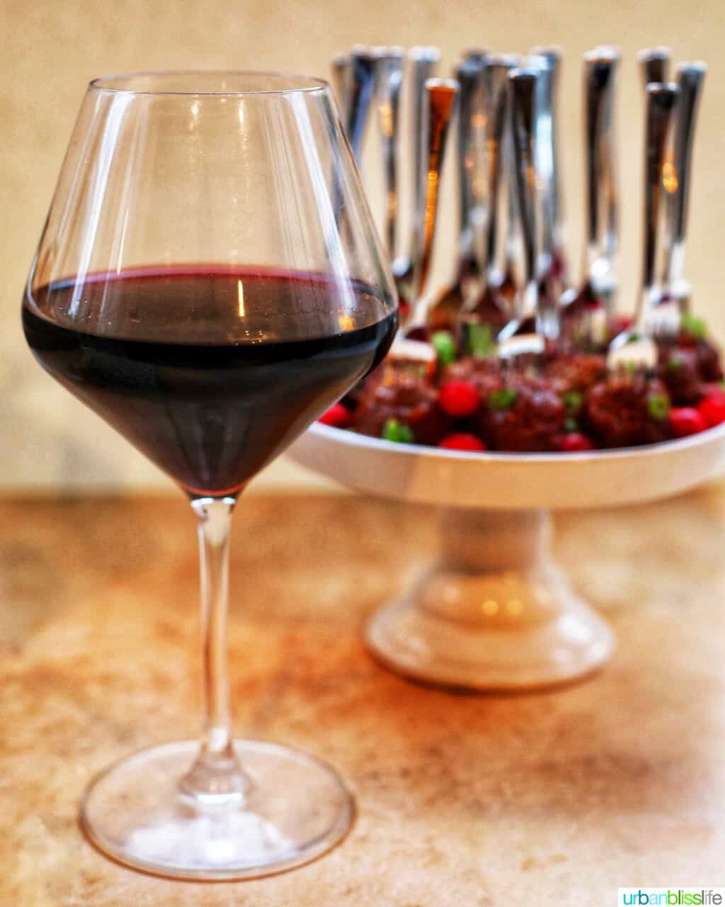 red wine glass with cake stand full of cranberry meatballs