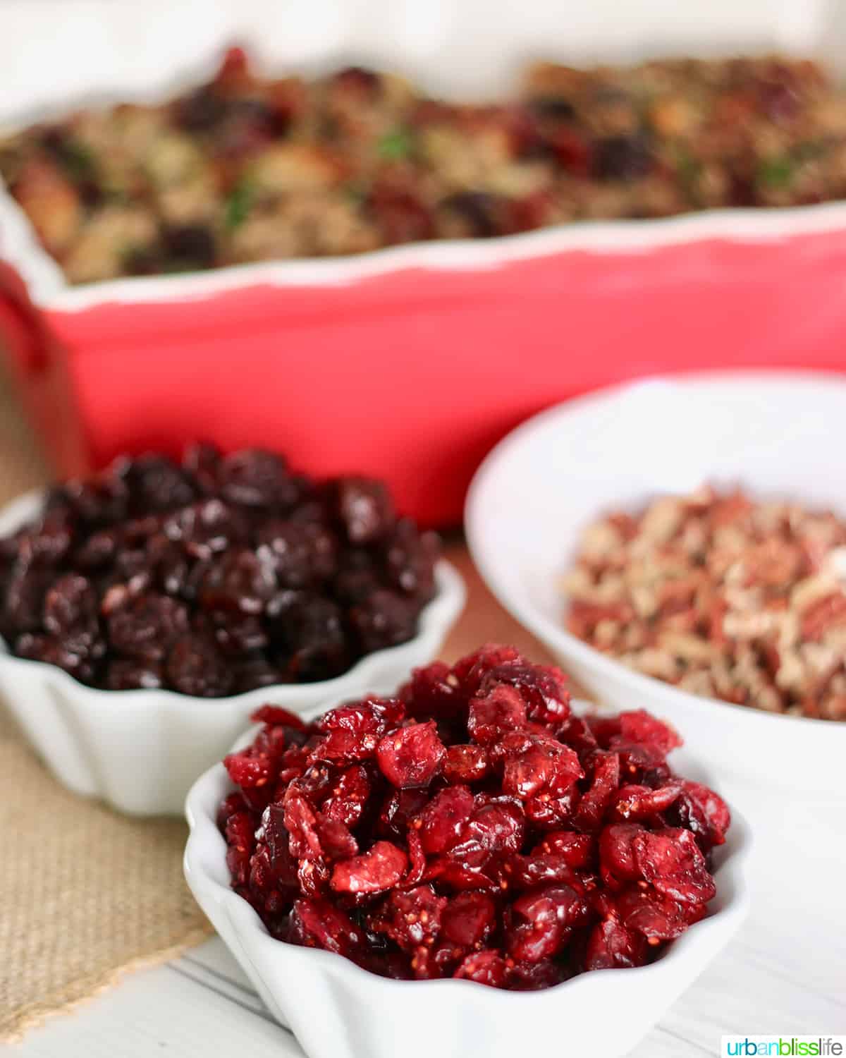white bowls filled with cranberries and cherries next to thanksgiving stuffing.