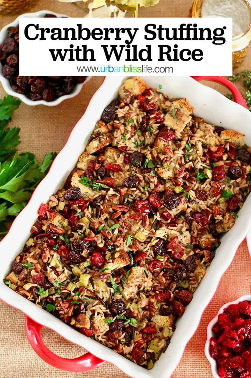 cranberry stuffing with wild rice and cherries in a casserole dish with bowls of cherries and herbs on the side.