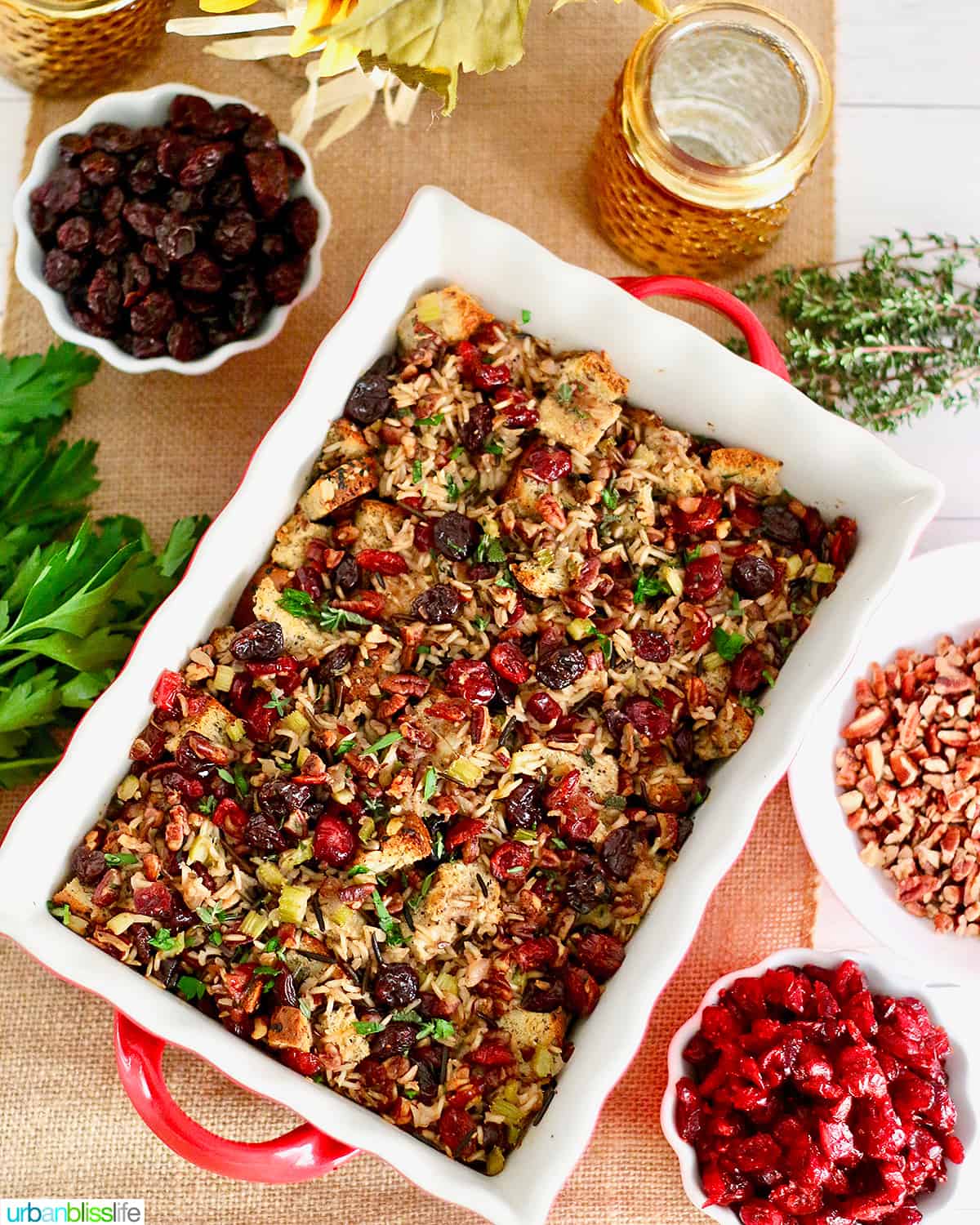 cranberry stuffing with wild rice and cherries in a casserole dish with bowls of cherries and herbs on the side.