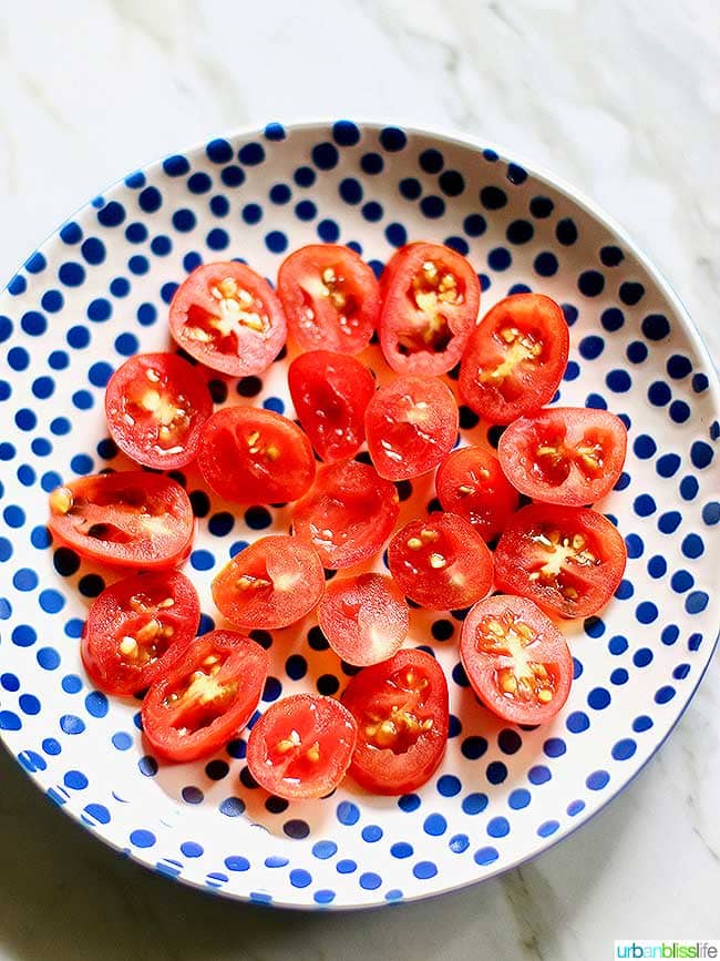halved cherry tomatoes on a blue polka dot plate.