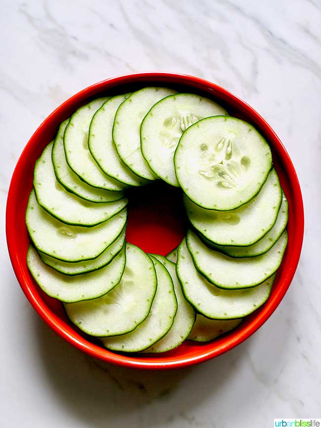 sliced cucumbers in a spiral on a red plate.