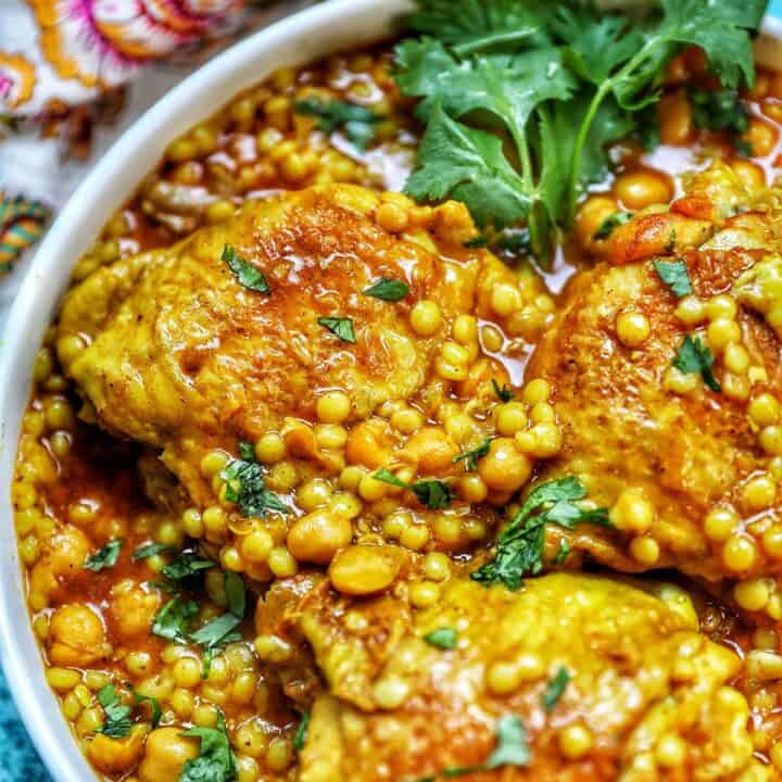 close up of left side of pressure cooker moroccan chicken in a large serving bowl with colorful napkin