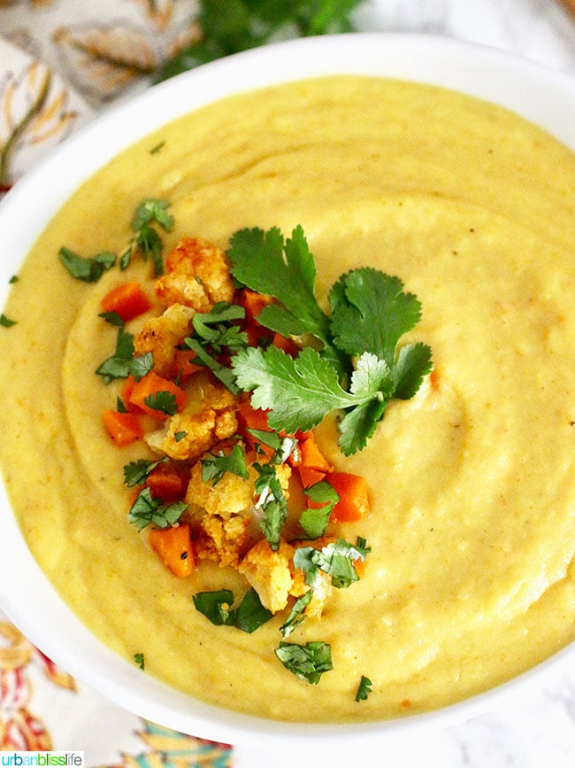 white bowl filled with Cauliflower Carrot Soup and topped with chopped cauliflower, carrots and parsley.
