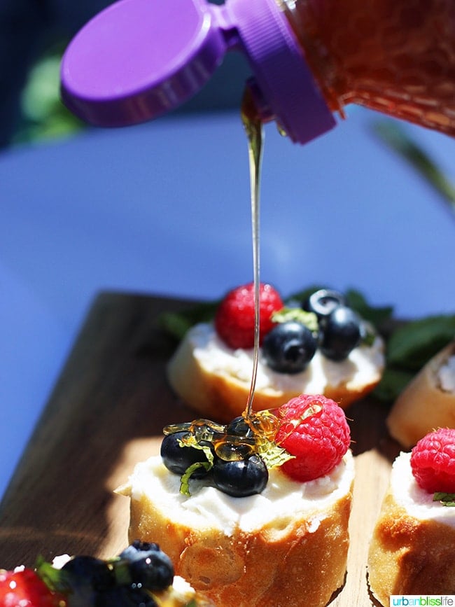 honey drizzling over berries and ricotta crostini