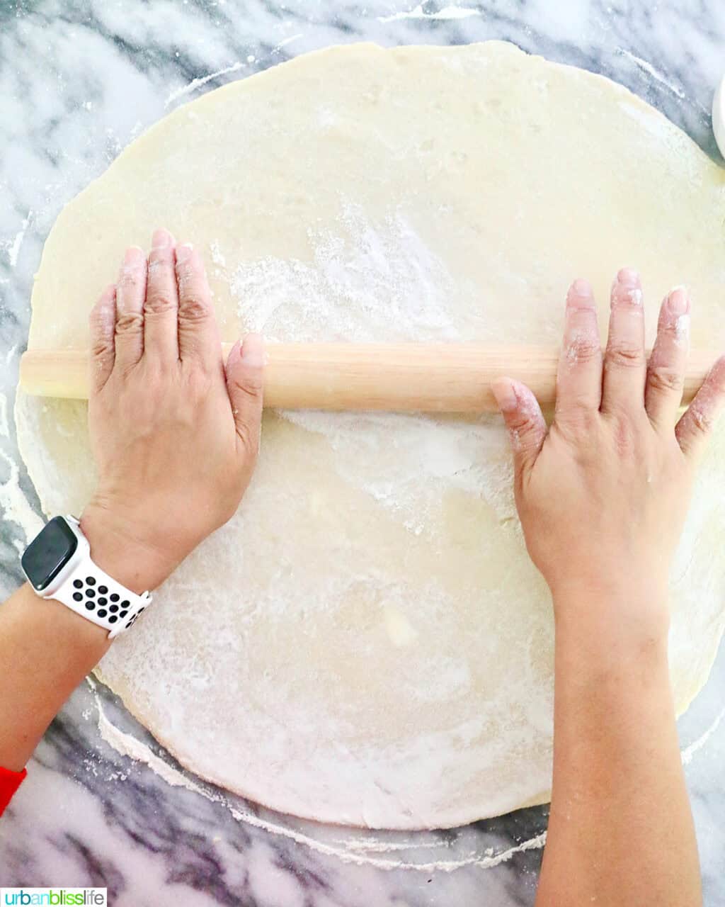 hands rolling out pie dough.