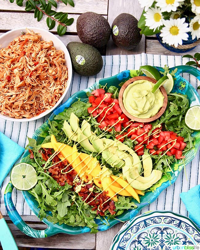 Creamy Avocado Lime Dressing & Dip drizzled over mangos, tomatoes, avocados, and bacon