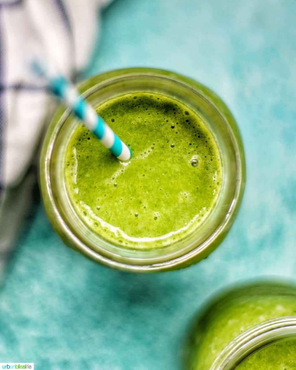 closeup looking into a mason jar with super green smoothie on a blue background