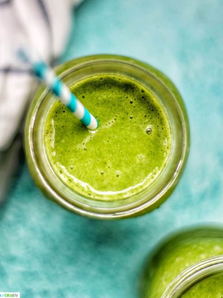 closeup looking into a mason jar with super green smoothie on a blue background