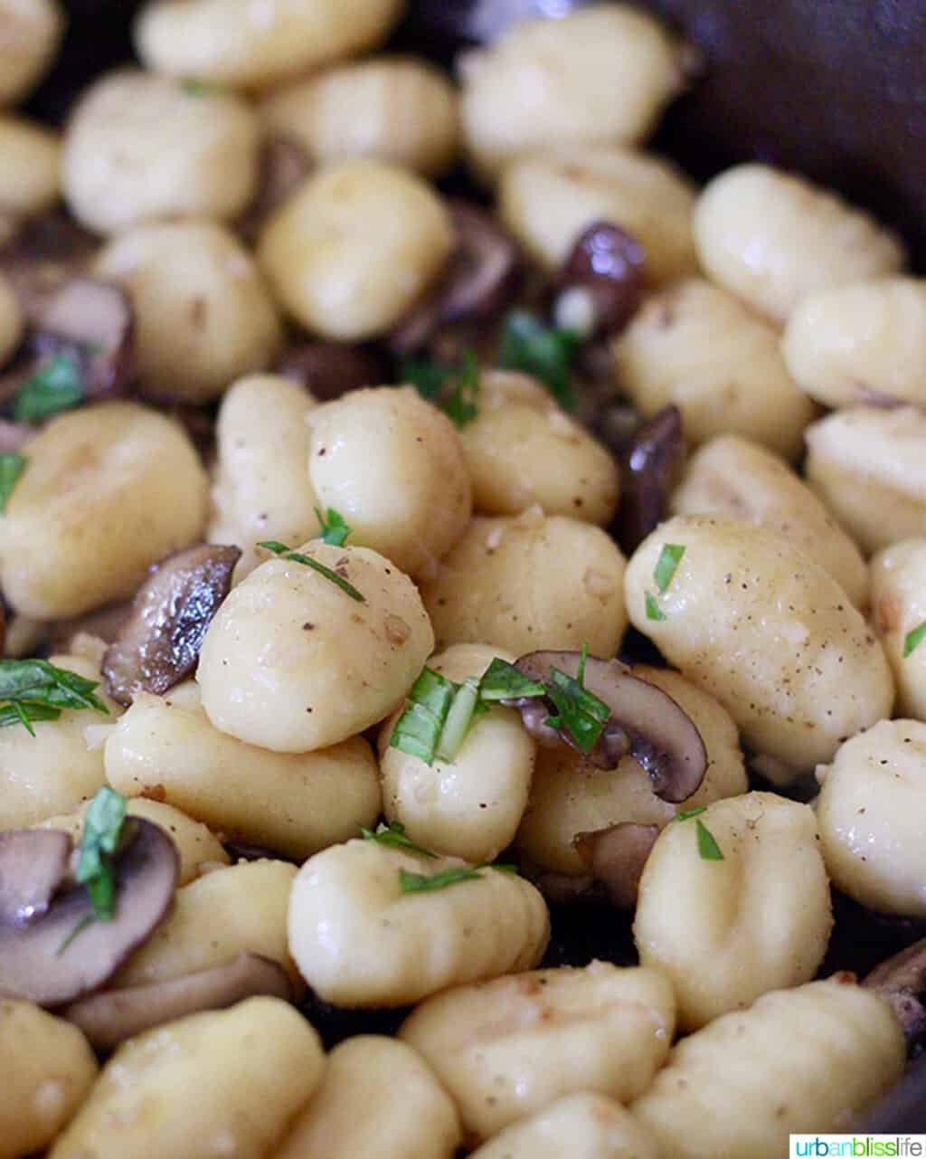 gnocchi and mushrooms cooking in a cast iron skillet.