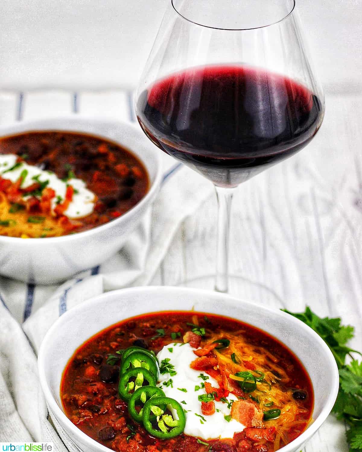 two bowls of chili with glass of red wine.