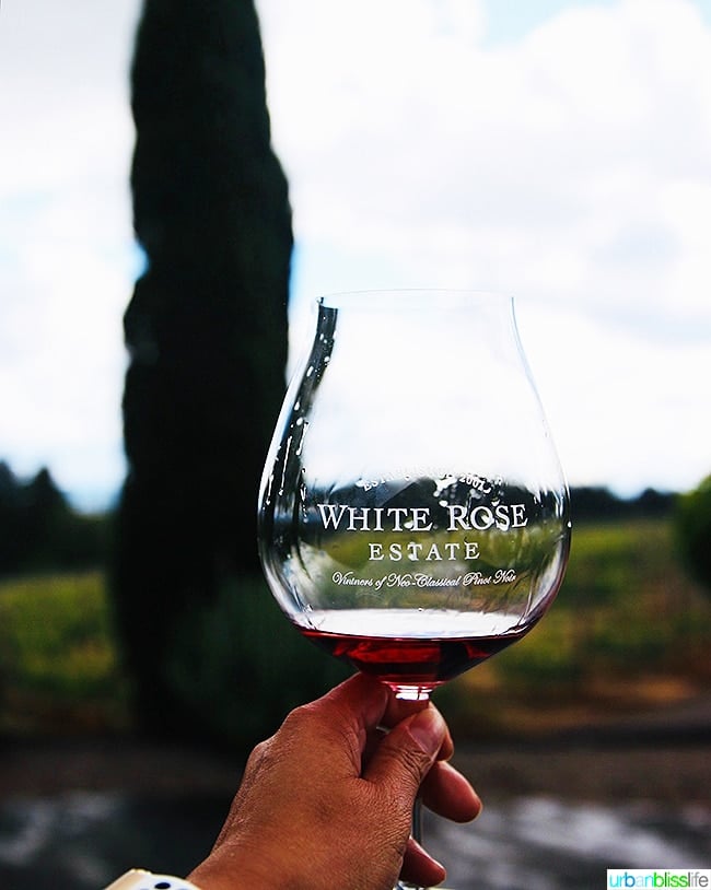 holding up a Pinot Noir glass with White Rose Cellars red wine