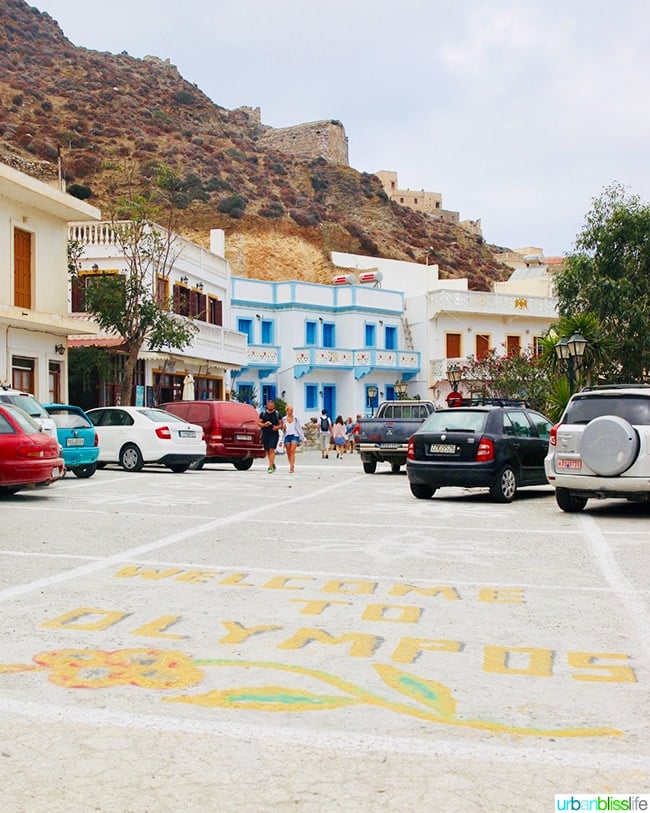 Cars parked on the sides of the street entrance to a small village in Olympos on Karpathos, Greece.