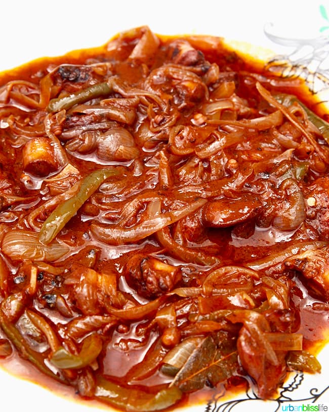 big white bowl full of cooked octopus in red sauce, olympos karpathos island greece.